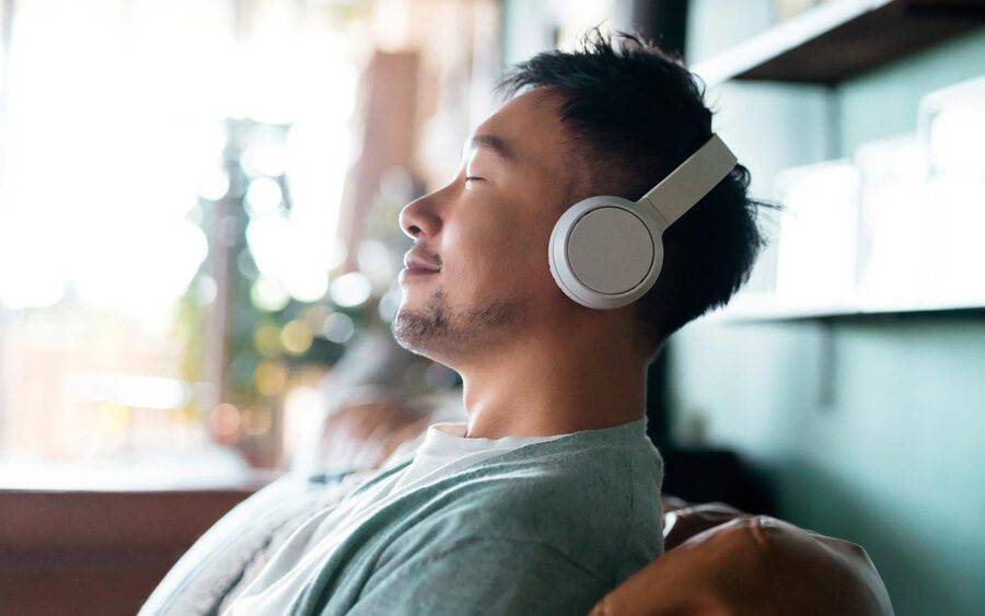 A man listening to some peaceful music or guided meditation in order to feel calm throughout the day.
