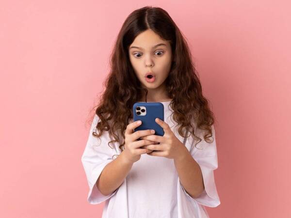A girl looks at her smartphone with surprise.